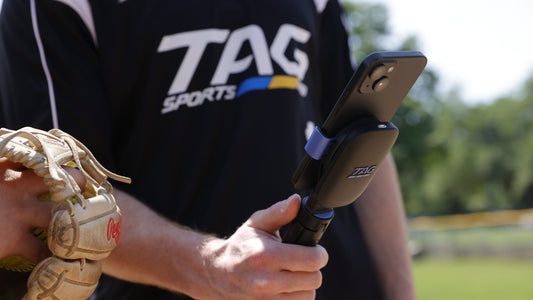 Two athletes view phone screen to review pitching data from a recent practice.