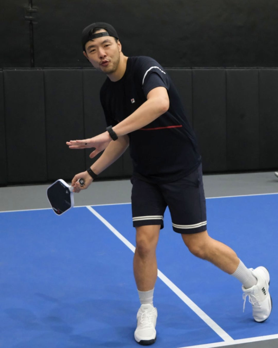Man playing pickleball on a court with a black background