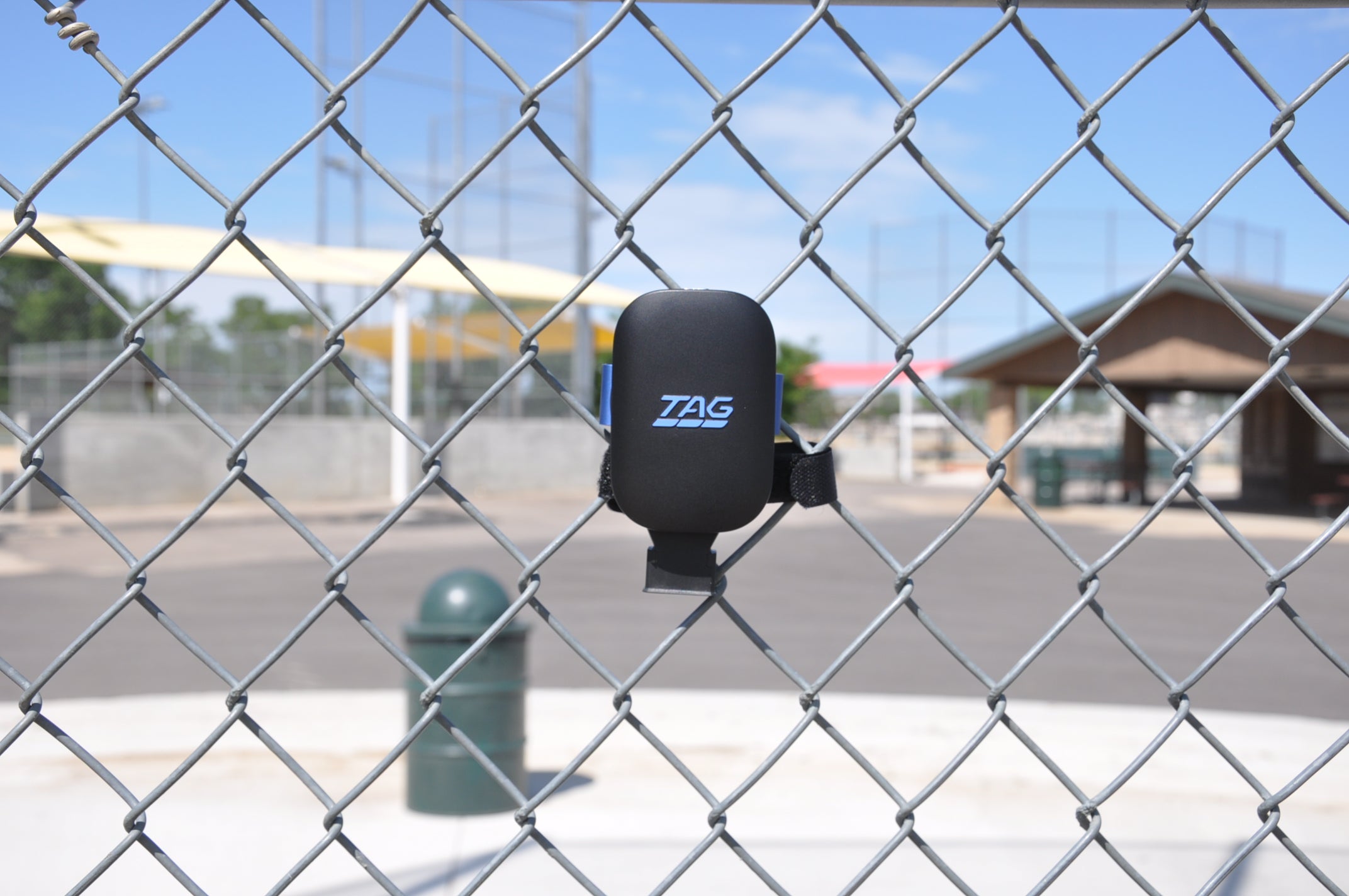 TAG One Sports Radar device attached to bracket and velcro strap, affixed to baseball backstop chainlink.