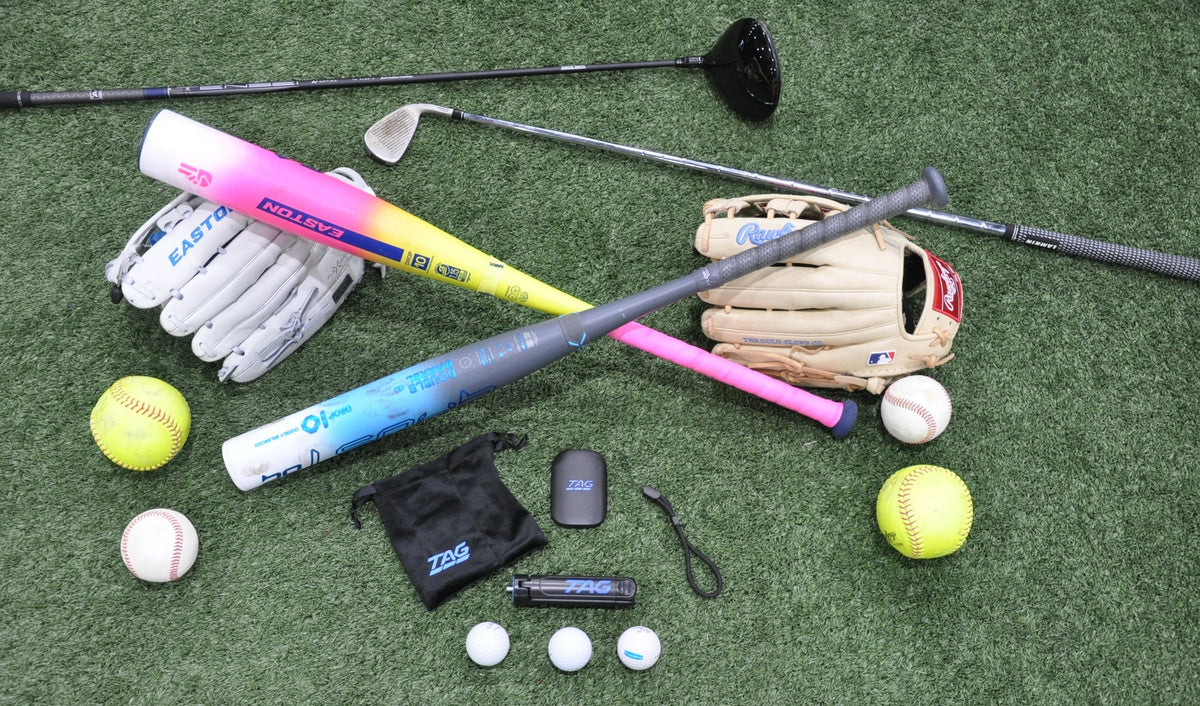 TAG One Sports Radar and included accessories on green turf, surrounded by assorted softball, baseball, and golf gear.