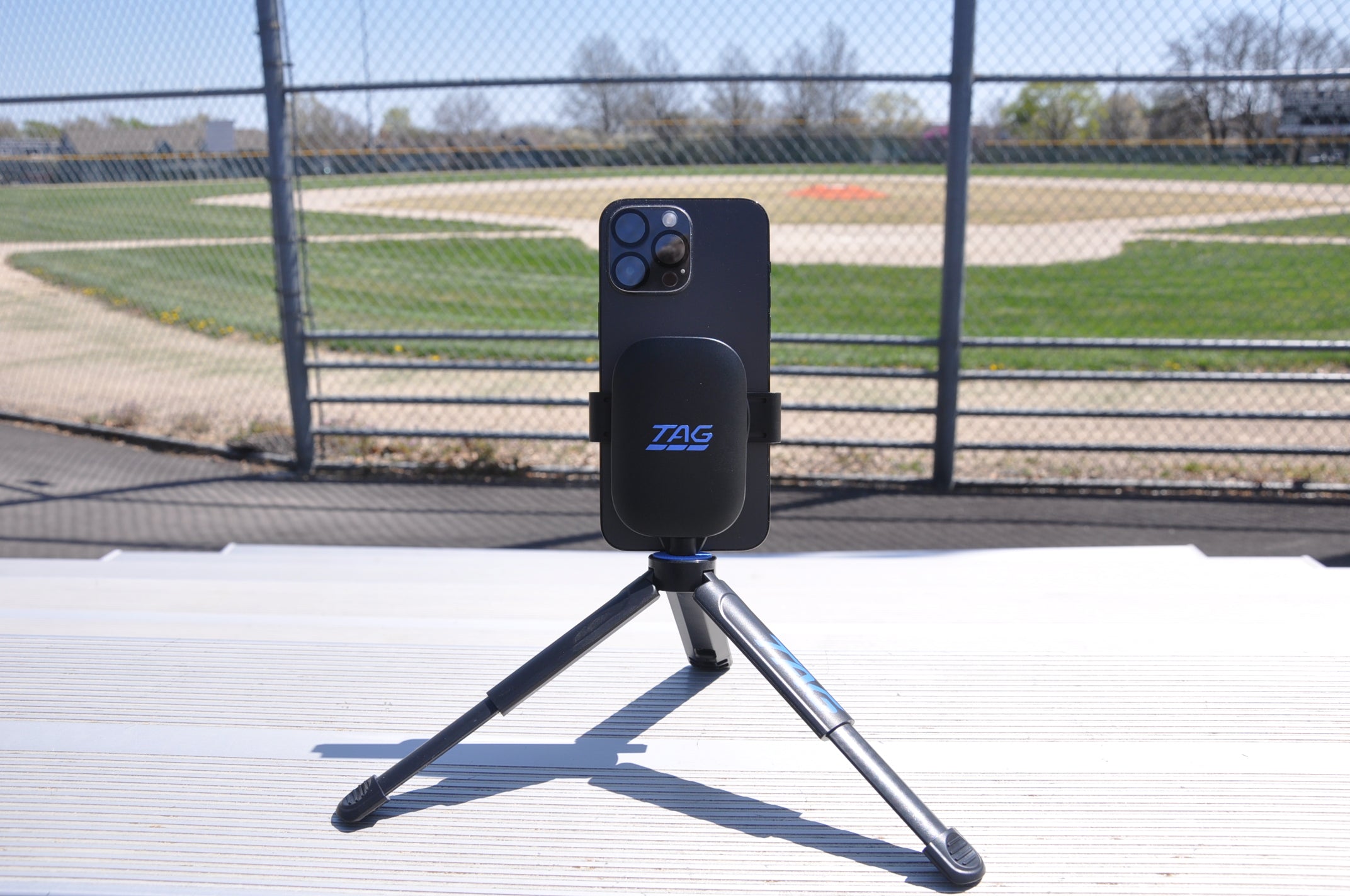 Full kit TAG One assembly with expanded tripod, sitting atop aluminum bleachers at a baseball field.