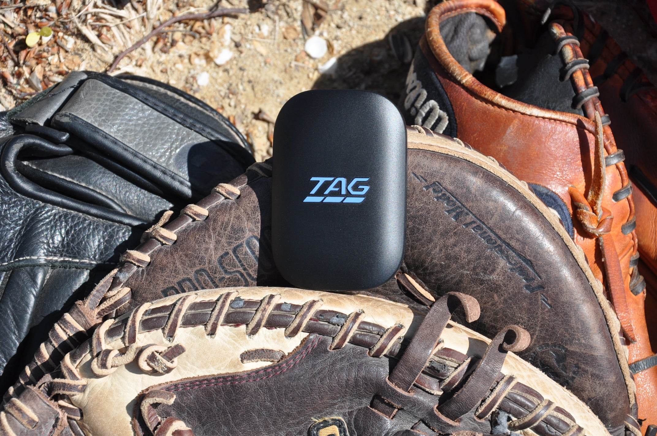 TAG One Sports Radar Device sitting atop three different baseball mitts.