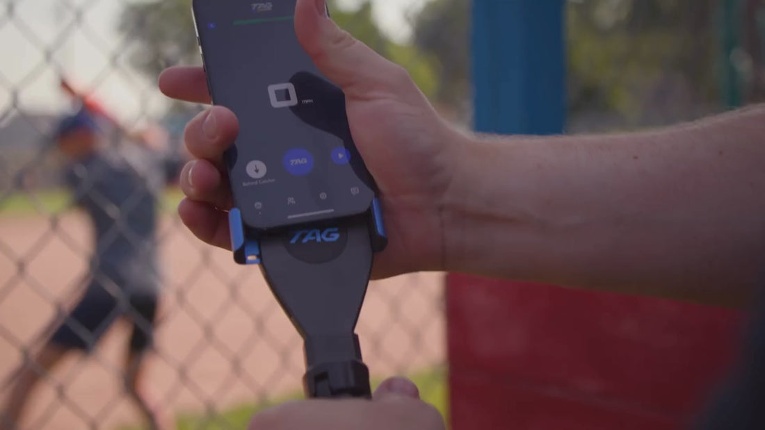 Phone being attached to phone bracket and tripod, baseball player practicing swings with bat in background.